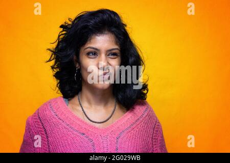 Bella Sri Lanka ragazza posa in piedi con giallo luminoso sfondo- La giovane donna sorride facendosi faccia Foto Stock