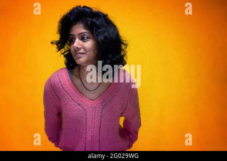 Bella Sri Lanka ragazza posa in piedi con giallo luminoso sfondo- La giovane donna sorride Foto Stock