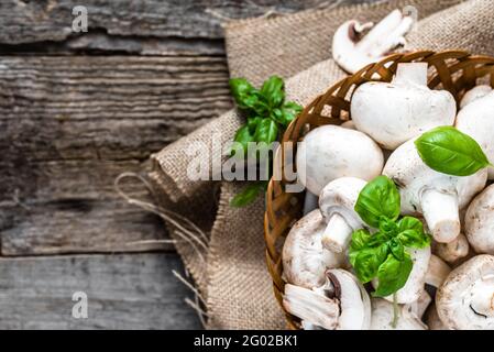 Fresco di funghi champignon in un cestino sul tavolo di legno, overhead Foto Stock
