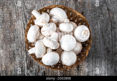 Fresco di funghi champignon in un cestino sul tavolo di legno, overhead Foto Stock