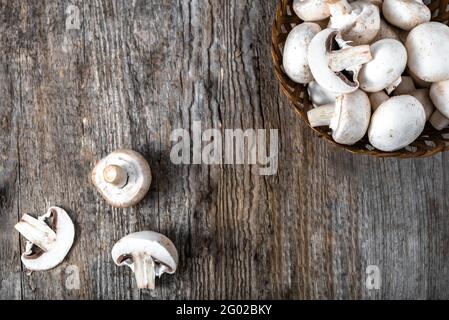 Fresco di funghi champignon in un cestino sul tavolo di legno, overhead Foto Stock