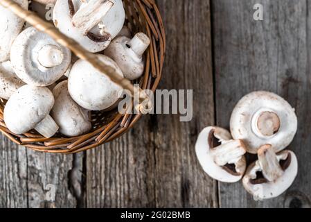 Fresco di funghi champignon in un cestino sul tavolo di legno, overhead Foto Stock