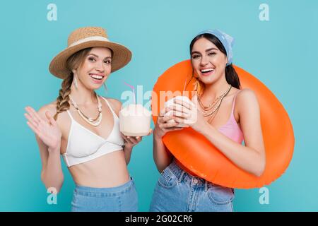 Amici allegri con cocktail in noci di cocco e nuoto anello isolato su blu Foto Stock