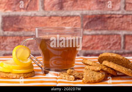 Biscotti di farinata d'avena accompagnati da una tazza di tè e tagliati a fette limone Foto Stock