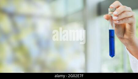 Composizione della mano del tecnico di laboratorio che tiene la provetta di liquido blu, con spazio di copia sfocato Foto Stock