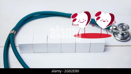 Composizione di icone cardiache su stetoscopio e blocchi bianchi con spazio di copia su sfondo bianco Foto Stock