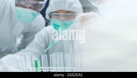 Composizione di scienziati in tute ppe con provette funzionanti in laboratorio e spazio di copia Foto Stock