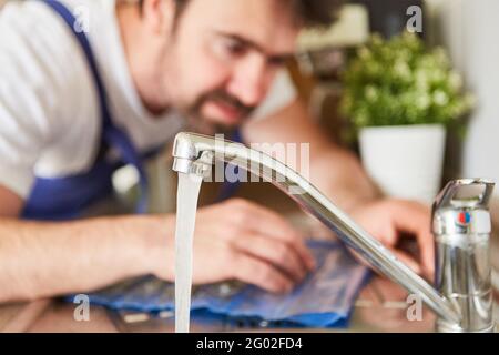 L'artigiano o il do-it-yourselfer controlla il rubinetto del miscelatore per l'acqua calda a. il lavandino Foto Stock