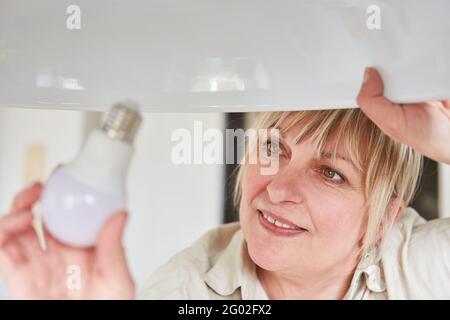 Donna trasforma la lampadina LED in lampadina per risparmiare energia a. casa Foto Stock