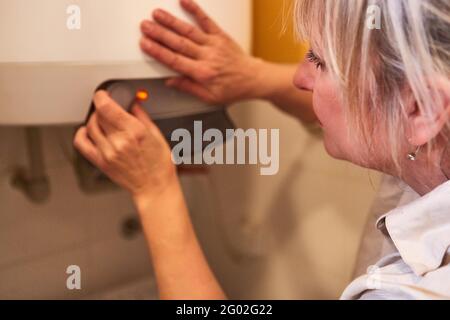 Donna fai da te ripara o regola il riscaldatore dell'acqua del caldaia a gas in bagno Foto Stock