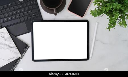 Simulato su tablet digitale, telefono cellulare, notebook, tazza da caffè e pianta domestica su tavolo bianco. Foto Stock