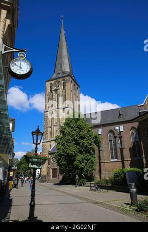 Viersen (Suchteln), Germania - Maggio 20. 2021: Vista sulla strada pedonale sulla torre medievale della chiesa gotica con orologio al muro della casa (concentrarsi sulla torre della chiesa Foto Stock