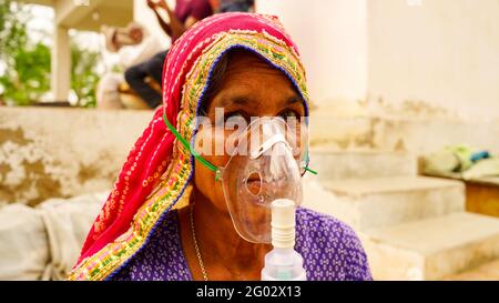 20 maggio 2021 - Reengus, Sikar, India. Vecchia donna indiana infettata con la malattia di Covid 19. Maschera per l'inalazione di ossigeno con flusso di ossigeno liquido. Foto Stock
