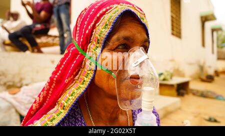 20 maggio 2021 - Reengus, Sikar, India. Vecchia donna indiana infettata con la malattia di Covid 19. Maschera per l'inalazione di ossigeno con flusso di ossigeno liquido. Foto Stock