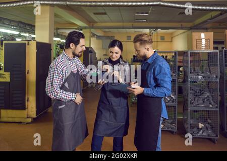 Team di calzolai che lavora presso la fabbrica di scarpe ispezionando scarpe che parlano e. sorridente Foto Stock