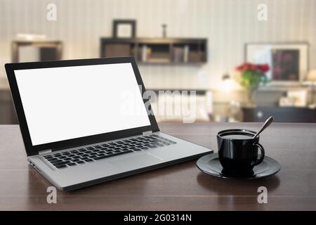 Computer portatile con schermo vuoto vuoto sul piano del tavolo in legno e moderno salotto sfocato come sfondo. Modello, mock in su per disoaly i vostri prodotti domestici. Lavoro A. Foto Stock