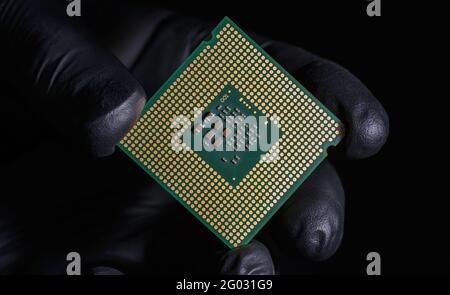 Una mano in un guanto nero tiene un processore. Il concetto di hacking, furto di dati, criminalità informatica. Foto Stock