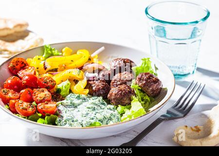 Concetto di cibo greco. Polpette, salsa tzatziki, insalata di pomodori e cetrioli. Foto Stock