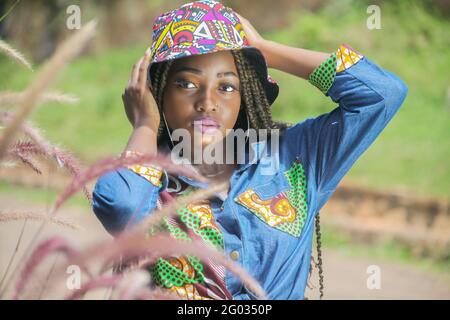 KAMPALA, UGANDA - 27 maggio 2021: Bella ragazza afroamericana negli outfit africani in posa per la foto con la natura verde che la circonda Foto Stock