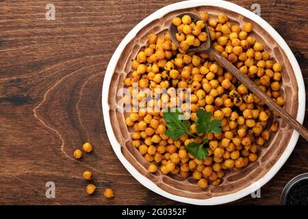 Ceci fritti con curcuma in piastra di ceramica su un vecchio tavolo di legno sullo sfondo. Ceci piccanti arrosto o chana Indiana o Chole, popolari spuntini reci Foto Stock