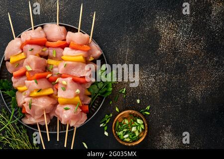 Kebab crudo di shish su tavola di legno, spezie, erbe e verdure su sfondo grigio scuro. Barbecue ingredienti crudi per goulash o shish kebab. Vista dall'alto. Foto Stock