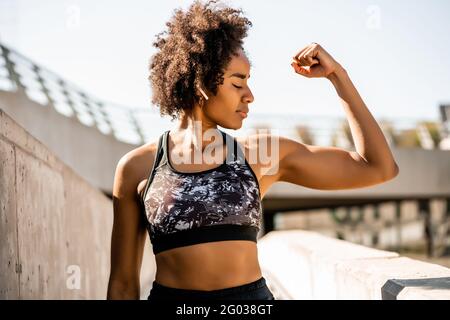 Afro atleta donna che flette e mostra i muscoli. Foto Stock