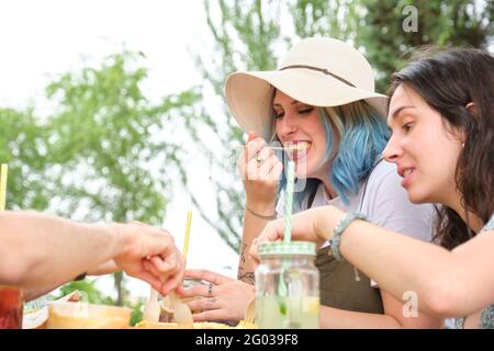 Gruppo di amici felici che si divertono e mangiano in un parco. Picnic in una giornata estiva soleggiata. Foto Stock