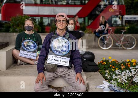 LONDRA, UK - i manifestanti della ribellione estinzione meditano con segni che dicono dolore e amore per la terra durante una manifestazione a Piazza del Parlamento Foto Stock