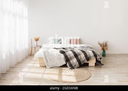 Design boho contemporaneo in stile minimalista. Letto con cuscini e coperta, tavolo con piante secche in vasi Foto Stock