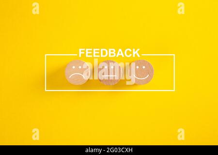 Immagine concettuale del feedback e della soddisfazione del cliente - volti felici, tristi e neutri su sfondo giallo Foto Stock