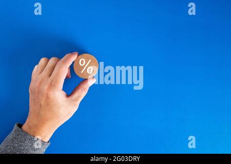 Mano maschio che mette un blocco di legno con segno di percento. Sconto aziendale, interesse, ipoteca o concetto di tasso di profitto. Foto Stock