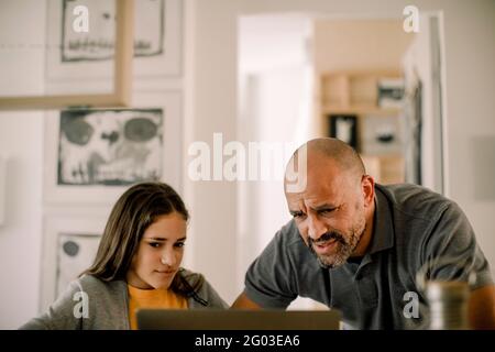 Padre e figlia utilizzando laptop in cucina a casa Foto Stock