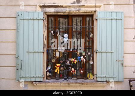 Curiosa o insolita finestra di casa cittadina decorata con Knick-Knacks e giocattoli coccolati nella città vecchia Saint Remy de Provence Provence France Foto Stock