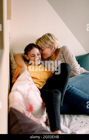 Madre sorridente e figlia che si stendono a letto a casa Foto Stock