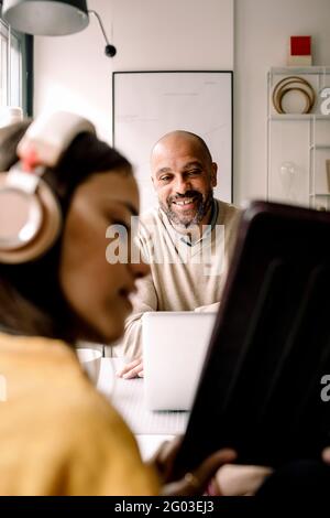 Sorridente padre che guarda la figlia che mostra il tablet digitale a casa Foto Stock