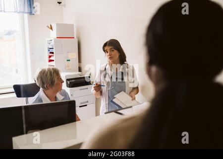 Medico femminile che discute con l'infermiere senior mentre guarda il paziente in clinica medica Foto Stock