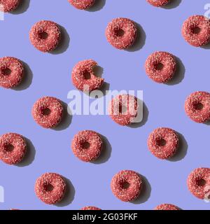 Motivo Donut rosa su sfondo viola. Concetto di tendenza alla luce del sole minimale. Vista dall'alto Foto Stock