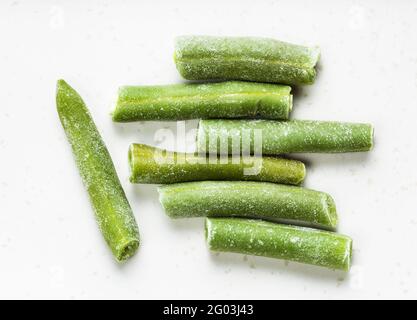 diversi fagioli verdi tagliati e congelati si avvicinano al grigio piastra in ceramica Foto Stock