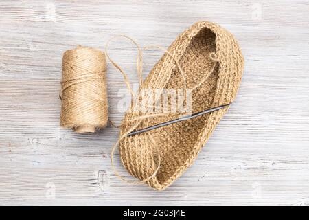 vista dall'alto del rocchetto di spago per canapa, del fondo lavorato a mano del sacchetto e del crochet su un tavolo di legno Foto Stock