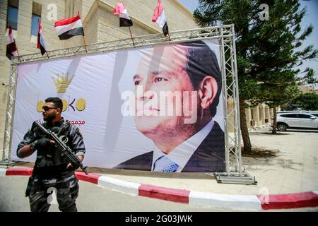 Gaza, Palestina. 31 maggio 2021. Un membro della sicurezza di Hamas è protetto da un cartello che mostra il presidente Abdel Fattah al-Sisi durante un incontro tra il capo dell'intelligence egiziana e i funzionari di Hamas a Gaza. il maggiore generale Abbas Kamel, riunitisi a Gaza, il 31 maggio 2021, kamel è in visita ufficiale in Israele e nei territori palestinesi per dare seguito all'accordo di cessate il fuoco, negoziato dall'Egitto, tra i gruppi armati palestinesi e Israele. Credit: SOPA Images Limited/Alamy Live News Foto Stock