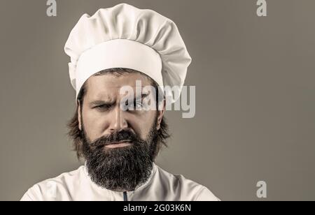 Cuoco, cuochi o panettiere con bearded. Cuochi maschi bearded isolati. Cuoco maschile sicuro in uniforme bianca. Cuoco serio in uniforme bianca, cappello dello chef Foto Stock