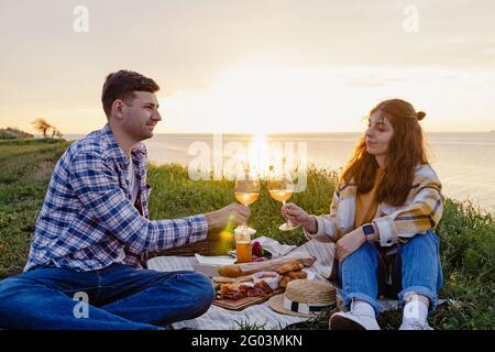 Coppia che ha pic-nic su prato verde con una vista mare Foto Stock