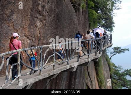 Monte Sanqingshan nella provincia di Jiangxi, Cina. La gente cammina lungo un sentiero aggrappato alla scogliera sul Monte Sanqing. Foto Stock