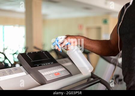 Primo piano di una persona che pulisce una macchina da palestra con disinfettante. Messa a fuoco selettiva. Spazio per il testo. Foto Stock