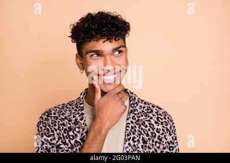 Ritratto di brunet ottimista ragazzo mano mento sguardo vuoto spazio indossare una camicia moderna isolata su sfondo color beige pastello Foto Stock