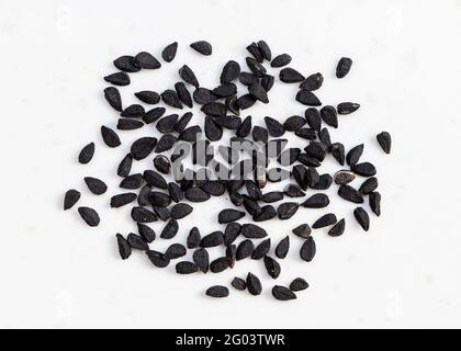 Diversi semi di Nigella sativa (caraway nero) primo piano sulla piastra in ceramica grigia Foto Stock