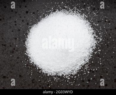 vista dall'alto del cumulo di sostituto dello zucchero - estratto cristallino di pianta di stevia primo piano su piastra di ceramica nera Foto Stock
