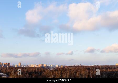 vista del cielo blu del tramonto con le nuvole sul parco cittadino e case urbane in primavera sera Foto Stock