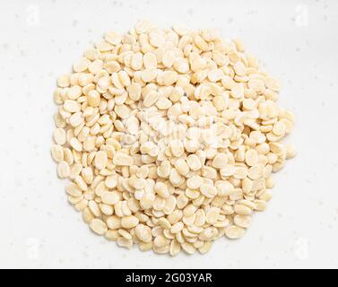 pila di urad dal grezzo (grammo nero diviso) i fagioli si avvicinano alla piastra in ceramica grigia Foto Stock