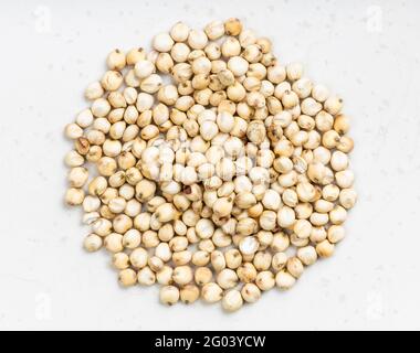 Vista dall'alto del cumulo di grani di Sorgo grezzi non lucidati su una piastra in ceramica grigia Foto Stock